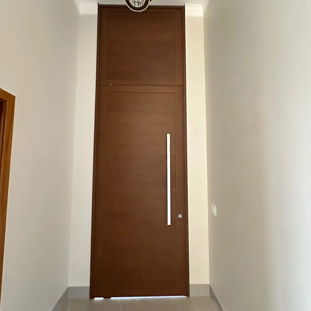 Porta amadeirada com puxador longo em ambiente interno